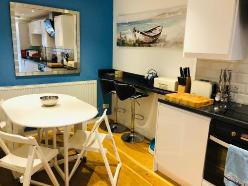 a kitchen with a table and a white table and chairs at Beach Road- short walk to Charlestown, Carlyon Bay & coastal paths in Carlyon Bay