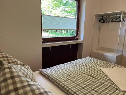 a bedroom with a bed with a checkered blanket and a window at Ferienwohnung auf dem Betzenberg in Kaiserslautern