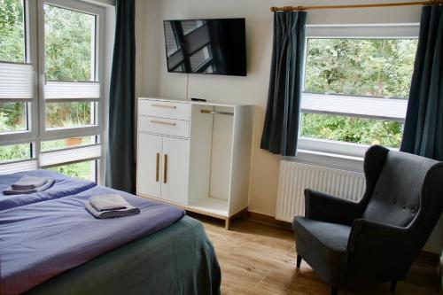 a bedroom with a bed and a chair and windows at Appartementhaus Meridian in Sankt Peter-Ording
