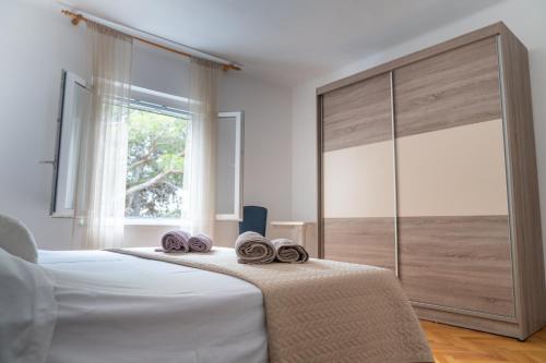 a bedroom with a bed with two towels on it at Sidus Maris, Spacious Seaside Apartment with Free Parking in Martinšćica
