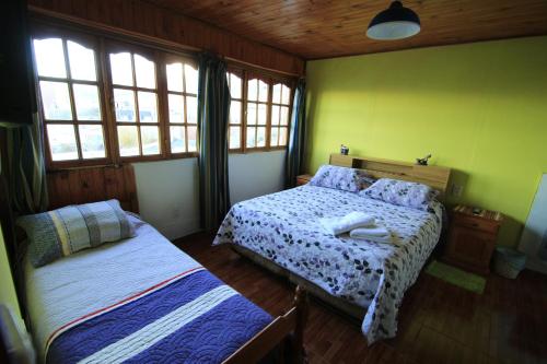 a bedroom with two beds and two windows at B&B Nahuel en Ushuaia in Ushuaia