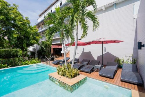 a swimming pool with chairs and umbrellas next to a building at Anchan Hotel & Spa in Hua Hin