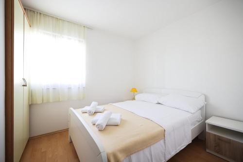 - une chambre blanche avec un lit et des serviettes dans l'établissement Apartments by the sea Petrcane, Zadar - 3285, à Petrčane