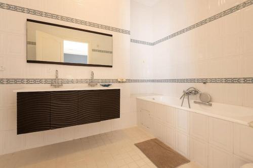 y baño con lavabo, bañera y espejo. en villa Pergola en Hammamet