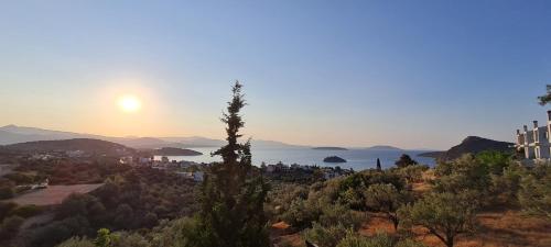 a view of a city with the sun setting over the water at Πέτρα, Ελιά και Λεβάντα in Tolo
