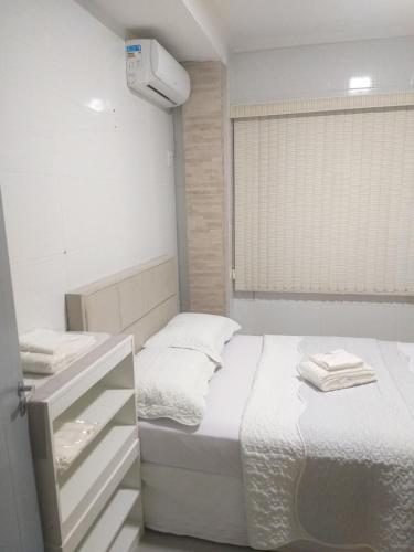 um quarto branco com uma cama e uma janela em Casa 2 Encanto dos Mares em Itapema