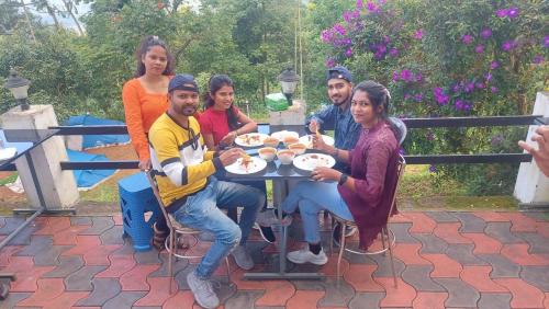 un grupo de personas sentadas alrededor de una mesa comiendo comida en MUNNAR TENT HILLS RESORT, en Devikolam
