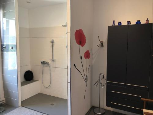 La salle de bains est pourvue d'une douche avec une fleur rouge sur le mur. dans l'établissement Maison au calme au coeur de village, à Saint-Georges-dʼOrques