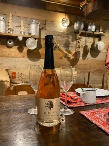 a bottle of wine sitting on a table with two glasses at ALLA STALLA Suite & Chalet in Piazzatorre