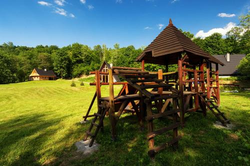 a wooden playground in a field with a gazebo at Dosbajka in Małastów
