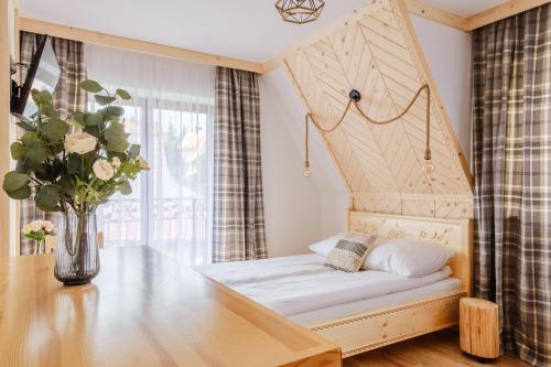 Bett in einem Zimmer mit einer Blumenvase in der Unterkunft Olczańska Kotlina Apart&Room in Zakopane