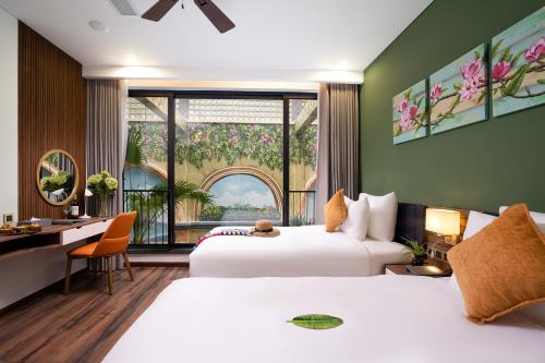 a hotel room with two beds and a desk and a window at Chi House Danang Hotel and Apartment in Da Nang