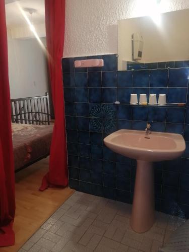a blue tiled bathroom with a sink and a bed at Duplex meublé Mercantour in Fontan