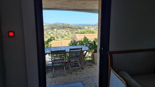 una puerta con vistas a una mesa y sillas en Bas de villa T3 Ollioules avec Piscine Vue mer en Ollioules