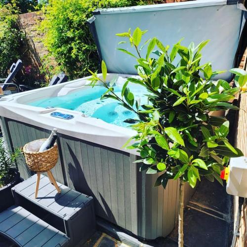 a jacuzzi tub in a garden with a plant at Executive Suite with Private HotTub, Full SkyTV in 600 Year Old Manor House in Saffron Walden