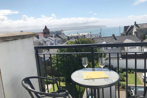 a table with two wine glasses on a balcony at Seaview Haven in Portstewart