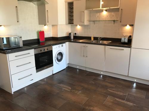 a kitchen with white cabinets and a washer and dryer at Seaview Haven in Portstewart