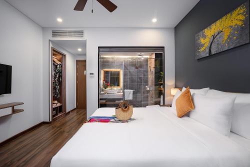 a bedroom with a large white bed and a bathroom at Chi House Danang Hotel and Apartment in Da Nang