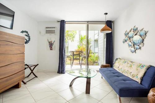 a living room with a blue couch and a glass table at DOWNTOWN Hawaiian Theme Condo with Hot Tub, Pool & Beach - Kona Islander Inn in Kailua-Kona