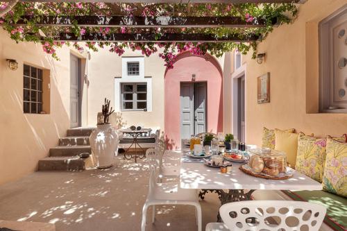 a patio with a table and chairs and flowers at Coat of Arms Mansion in Fira