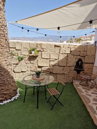 a patio with a table and chairs and a stone wall at Little Paradise in El Médano in Granadilla de Abona