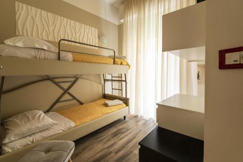 a room with three bunk beds and a desk at Hotel Corallo B&B in Cattolica