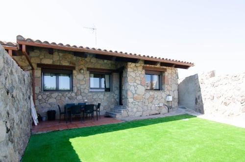 a stone house with a green lawn in front of it at Casa rural Los Cántaros. Zarapicos in Zarapicos