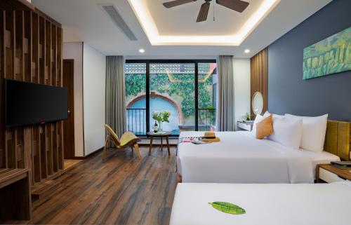 Habitación de hotel con 2 camas y TV de pantalla plana. en Chi House Danang Hotel and Apartment en Da Nang