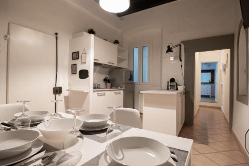a white kitchen with a dining table and chairs at 2 Rooms next to a market and Piazza Santa Croce - HomeUnity in Florence