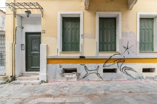 a building with green doors and graffiti on it at Athens Kerameikos Neoclassical House in Athens