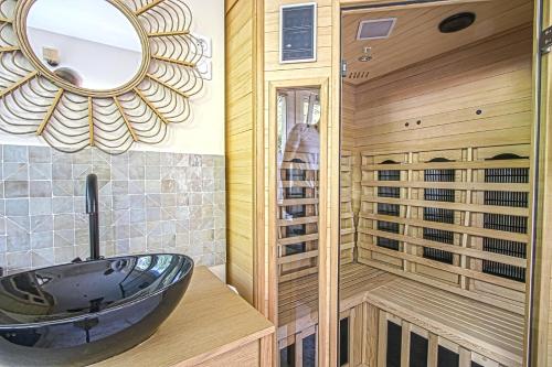 a bathroom with a black sink and a sauna at Le Boudoir de Fanny - Sauna/Balnéo/ciné/Hamacs in Le Havre