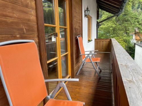 two orange chairs sitting on the porch of a house at Haus Monika in Kirchberg in Tirol