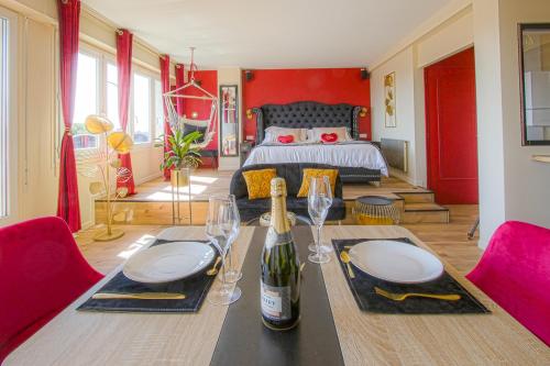 una habitación con una mesa con copas de vino y una cama en Le Boudoir de Fanny - Sauna/Balnéo/ciné/Hamacs, en Le Havre