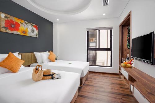 a hotel room with two beds and a television at Chi House Danang Hotel and Apartment in Da Nang