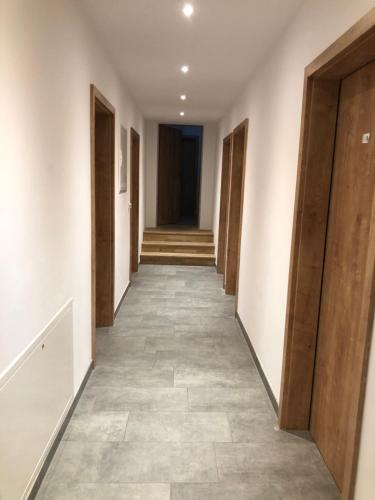 um corredor vazio com portas de madeira e pisos de azulejo em Pension Beil em Sauerlach