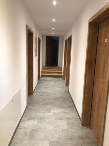 an empty hallway with wooden doors and tile floors at Pension Beil in Sauerlach