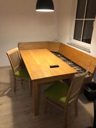 - une table en bois avec deux chaises et une télécommande dans l'établissement Pension Beil, à Sauerlach
