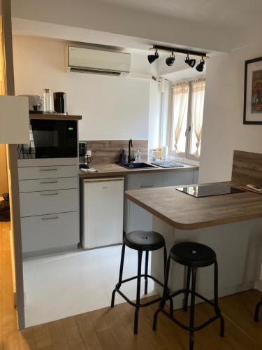 een keuken met 2 barkrukken en een aanrecht bij Studio Place Massena in Nice