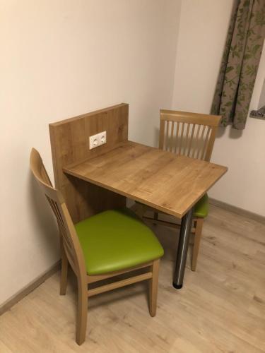 einem Holztisch mit zwei Stühlen und einem grünen Sitz in der Unterkunft Pension Beil in Sauerlach