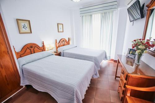 a bedroom with two beds and a dresser at Hostal Azul in La Antilla