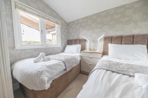 a bedroom with two twin beds and a window at North Lodge Cartmel in Cartmel