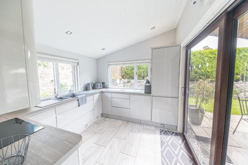 a kitchen with white cabinets and a large window at North Lodge Cartmel in Cartmel