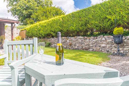 a bottle of wine sitting on a table with a glass at North Lodge Cartmel in Cartmel