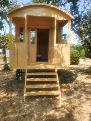 a wooden shed with a bench in front of it at la roulotte dépote in Monbéqui