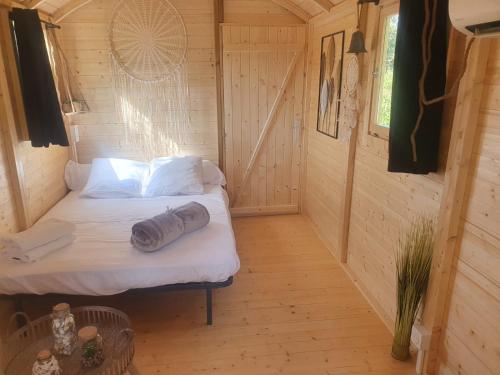 um pequeno quarto com uma cama num chalé de madeira em La roul'hôte dépote em Monbéqui