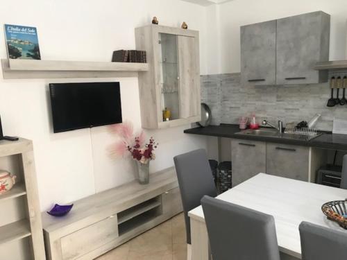 uma cozinha com uma mesa e uma televisão na parede em Appartamento 60 mq a 800 mt dalla spiaggia em Capaci