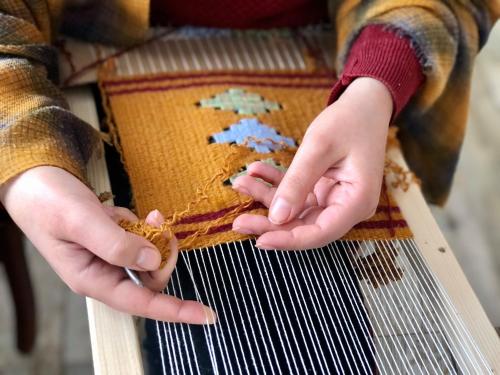 a young child is playing with a weaving instrument at Pottery House Sanahin in Alaverdi