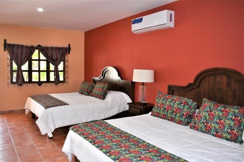 two beds in a room with orange walls at HACIENDA MONARCAS Resort in Puerto Peñasco