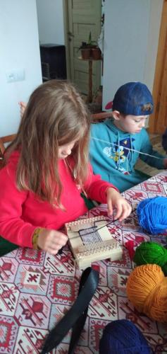 a young girl sitting on a bed with a keyboard at Pottery House Sanahin in Alaverdi