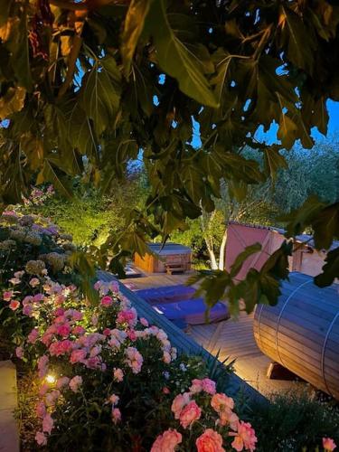 a garden with a bunch of flowers and a barrel at Gîte de charme 5 étoiles pour couple avec sauna et jacuzzi extérieurs privatifs in Peaugres